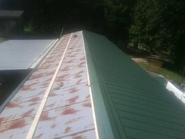 Old rusted panels beside newly installed green metal roofing — Wind Damage Roof Repair by Roofing Brothers in Indian Springs