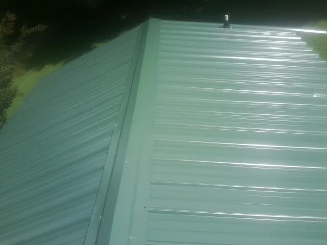 New green metal panels meeting at the ridge of a roof — Flat Roof Repair work by our crew in Indian Springs