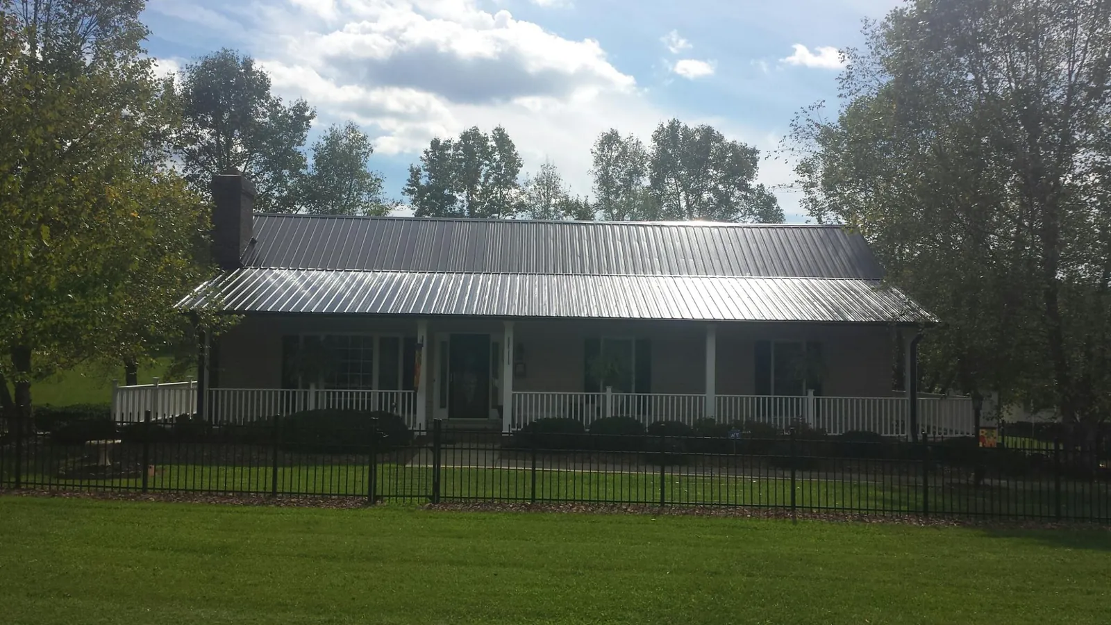 Gray metal roof on a brick ranch with a full width front porch — Gutter Guard Installation work by our crew in Indian Springs