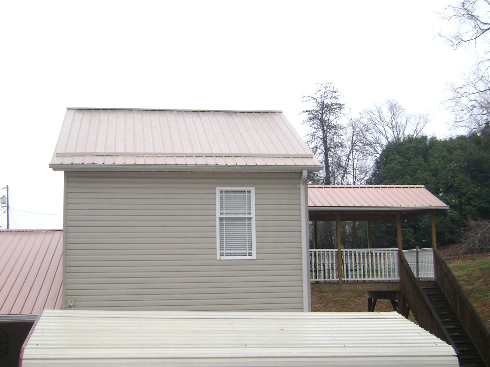 Tan metal roofs on a two story addition and attached porch, from a Roof Replacement job in Indian Springs