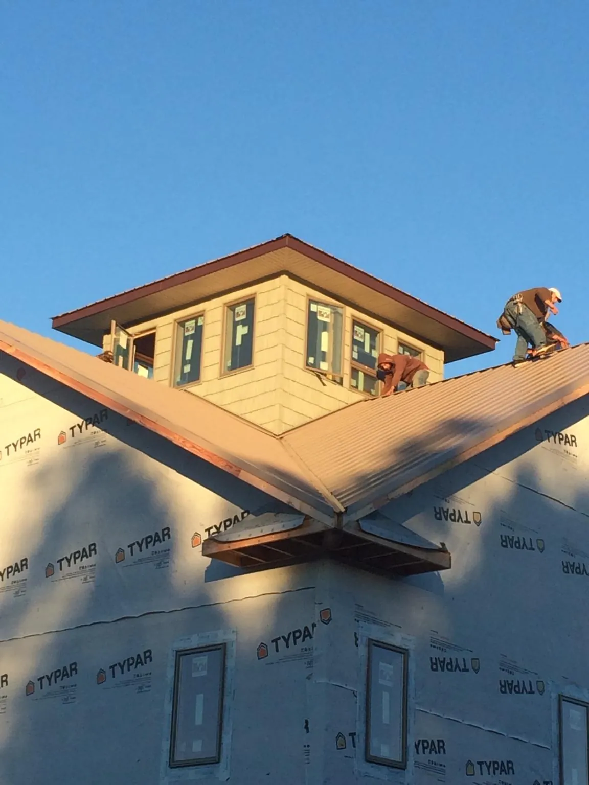 Roofers working around a rooftop cupola on a new metal roof at sunset — Roof Waterproofing in Indian Springs by Roofing Brothers
